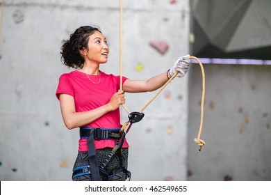 Portrait of beautiful woman rock climber belaying another climber with rope. Indoors artificial climbing wall and equipment. - Powered by Shutterstock