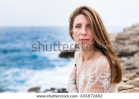 Portrait of beautiful woman. Seaside background. Looking at camera