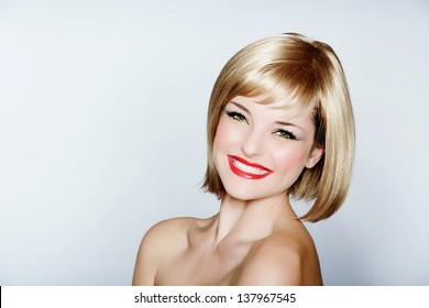 portrait of a beautiful woman in short blond bob with bright make-up on studio background 