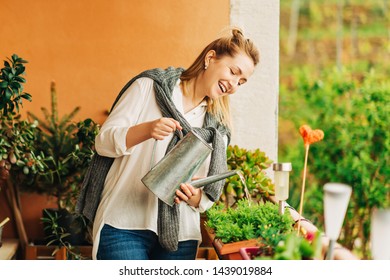 Portrait Of Beautiful Woman Watering Green Plants On The Balcony, Small Cozy Garden In Apartment