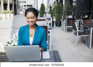 Portrait Of Beautiful Young African American Woman Working With Laptop While Sitting At The Table In Outdoor Coffee Shop