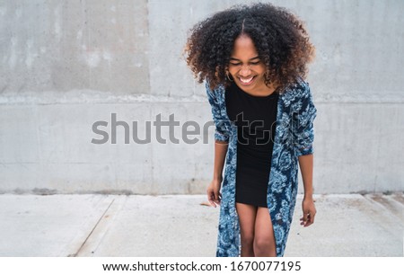 Similar – Young black woman, afro hairstyle, smiling near a wall in the street