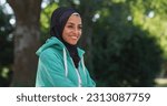 Portrait of Beautiful Young Arab Woman Smiling with a Greenery Background. Happy Muslim Female Athelet with Hijab Enjoying Fresh Air in the Park During her Early Morning Workout