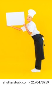 Portrait Beautiful Young Asian Chef Woman With White Empty Billboard On Yellow Isolated Background