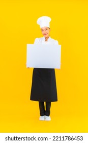 Portrait Beautiful Young Asian Chef Woman With White Empty Billboard On Yellow Isolated Background