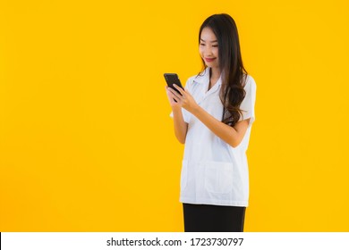 Portrait Beautiful Young Asian Doctor Woman Use Smart Mobile Cell Phone On Yellow Isolated Background