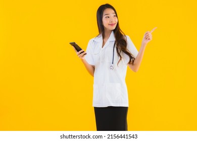 Portrait Beautiful Young Asian Doctor Woman Use Smart Mobile Cell Phone On Yellow Isolated Background