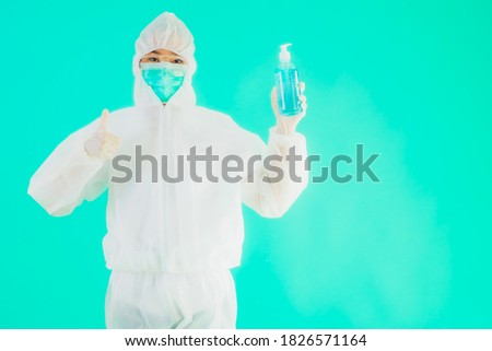 Portrait beautiful young asian doctor woman wear ppe suite and mask with alcohol gel on blue isolated background
