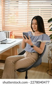 Portrait of beautiful young Asian female office worker in casual outfits using her phone at her office desk. - Shutterstock ID 2278040477