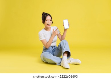 portrait of a beautiful young asian girl sitting on a yellow background - Powered by Shutterstock