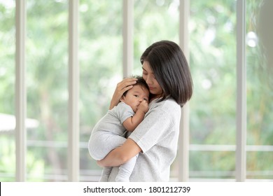 Portrait beautiful young Asian mother holding and hugging her newborn baby in living room. Healthcare and Happiness love asia woman lifestyle mother's day concept with copy space. - Shutterstock ID 1801212739
