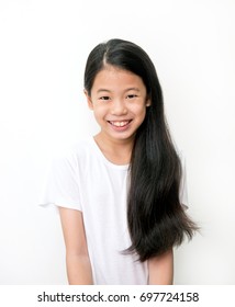 Porträt eines schönen jungen asiatischen Teenagermädchens mit langen, schwarzen Haaren auf weißem Hintergrund. Preteen in weißem T-Shirt mit gesundem schwarzen Haar lächeln. Gesundheits- und Schönheitskonzept.