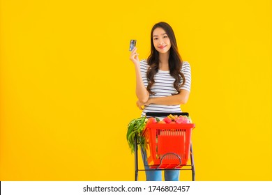 Portrait Beautiful Young Asian Woman Shopping Grocery Cart From Supermarket With Credit Card On Yellow Isolated Background