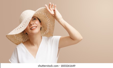 Portrait of beautiful young asian woman wearing straw hat wide brim to protect her flawless face from ultraviolet in the sunlight. Facial Sunscreens, SPF, Sunspots, Treatments, Skin care products.