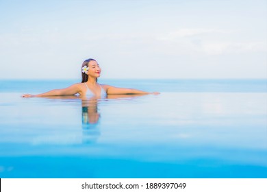 Portrait beautiful young asian woman relax smile around outdoor swimming pool in hotel resort nearly sea beach ocean