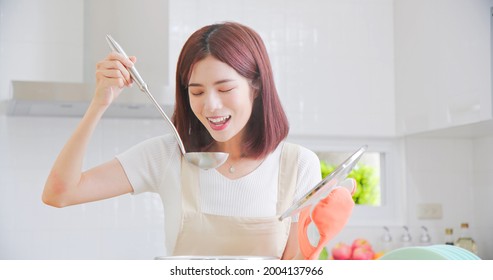 Portrait Of Beautiful Young Asian Woman Cooking Soup With Smiling In Light White Interior Style Kitchen