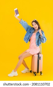 Portrait beautiful young asian woman with luggage travel bag with passport and boarding pass ticket on yellow isolated background