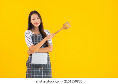 Portrait beautiful young asian woman  wear apron with black pan and Spatula on yellow isolated background - Shutterstock ID 2151359983