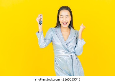 Portrait beautiful young asian woman smile with car key on yellow color background