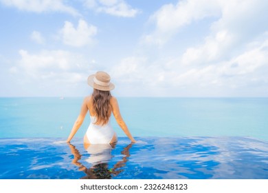 Portrait beautiful young asian woman relax smile leisure around outdoor swimming pool with sea ocean in travel vacation