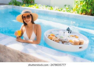 Portrait beautiful young asian woman happy smile with floating breakfast in tray on swimming pool - Powered by Shutterstock