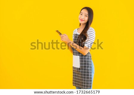 Portrait beautiful young asian woman use smart mobile phone on yellow isolated background