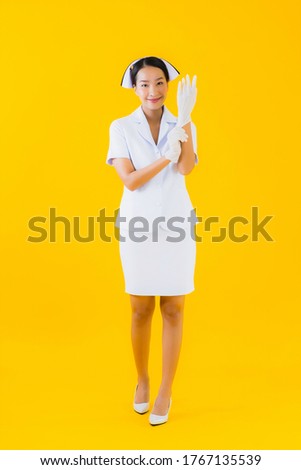 Portrait beautiful young asian woman thai nurse wear glove on yellow isolated background