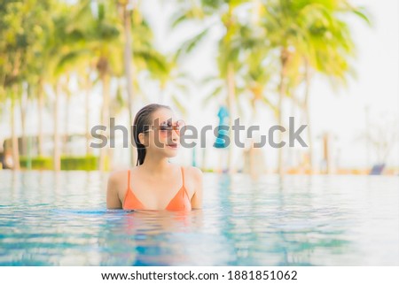 Portrait beautiful young asian woman relax smile leisure around outdoor swimming pool nearly sea beach ocean at sunset time for vacation