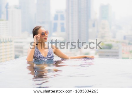 Portrait beautiful young asian woman relax smile enjoy leisure around outdoor swimming pool with city view
