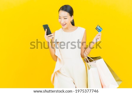 Portrait beautiful young asian woman smile with shopping bag on yellow color background
