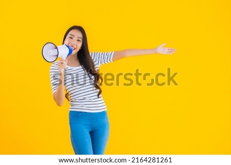 Portrait beautiful young asian woman use megaphone for contact or speak on yellow isolated background