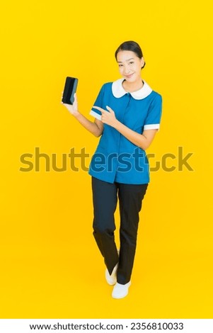 Portrait beautiful young asian woman maid and housekeeping smile with action on yellow color background