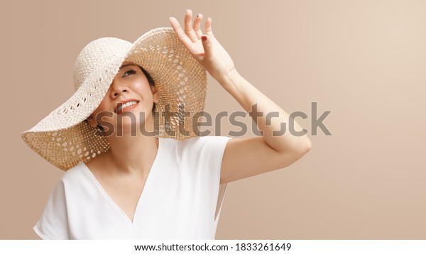 Portrait of beautiful young asian woman wearing\
straw hat wide brim to protect her flawless face from ultraviolet\
in the sunlight. Facial Sunscreens, SPF, Sunspots, Treatments, Skin\
care products.