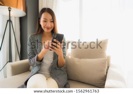 Portrait beautiful young asian women using talking mobile phone and sitting on sofa chair in living room area