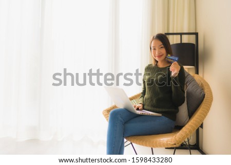 Portrait beautiful young asian women sitting on sofa chair using computer laptop or smart and mobile phone with credit card for online shopping