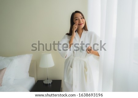 Portrait beautiful young asian women with coffee cup and mobile phone on bed in bedroom interior