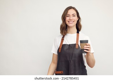 Portrait of beautiful young barista woman looking in camera and smiling, while holding a to-go coffee in hand. Isolated on white background. - Powered by Shutterstock
