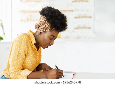 Portrait of a beautiful young black woman  writing in a notbook at home ot in the office