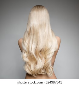Portrait Of Beautiful Young Blond Woman With Long Wavy Hair. Back view