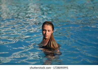 Portrait of a beautiful young blonde woman with wet hair in the pool. Relaxation harmony lifestyle concept