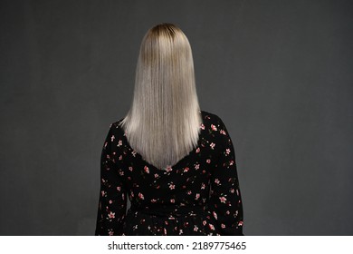 Portrait Of A Beautiful Young Blonde Woman With Long Wavy Hair, Rear View