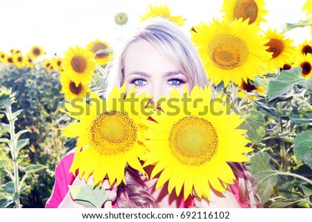 Fröhliche blonde Frau, die mit einem riesigen Gänseblümchen posiert.