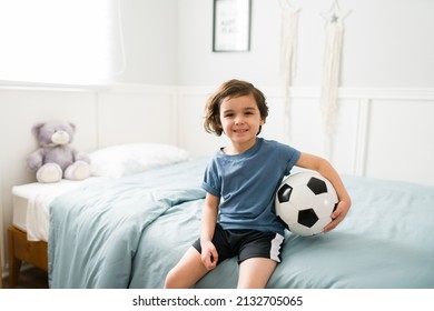 Portrait Of A Beautiful Young Boy Smiling And Making Eye Contact Ready To Go To Soccer Practice. Caucasian Child With A Soccer Ball