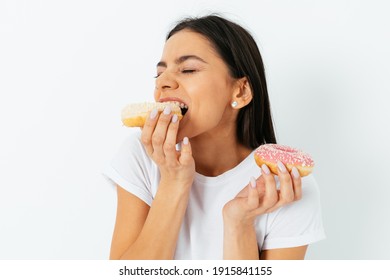 Portrait of beautiful young brunette woman biting eating donuts  isolated over white background.