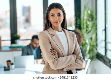 Portrait of beautiful young business woman standing while smiling looking at camera in the office