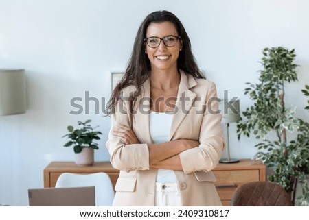 Portrait of beautiful young business woman standing while smiling looking at camera in the office
