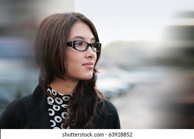 Portrait of beautiful young businesswoman outdoor over blurred street background. Closeup, shallow DOF.