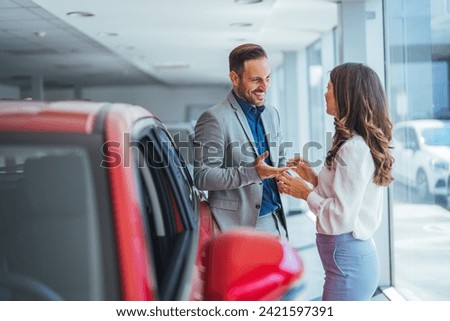 Portrait of a beautiful young couple choosing a new car at a car dealership. Buying a long-awaited car. Couple buying the automobile Pair in a car salon. Husband with vife choose the automobile