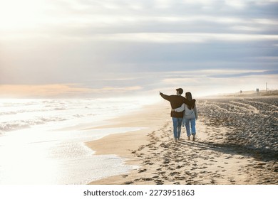 Portrait of beautiful young couple in love walking together in a cold winter day on the beach.