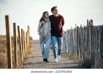 Portrait of beautiful young couple in love walking together in a cold winter day on the beach. - Powered by Shutterstock